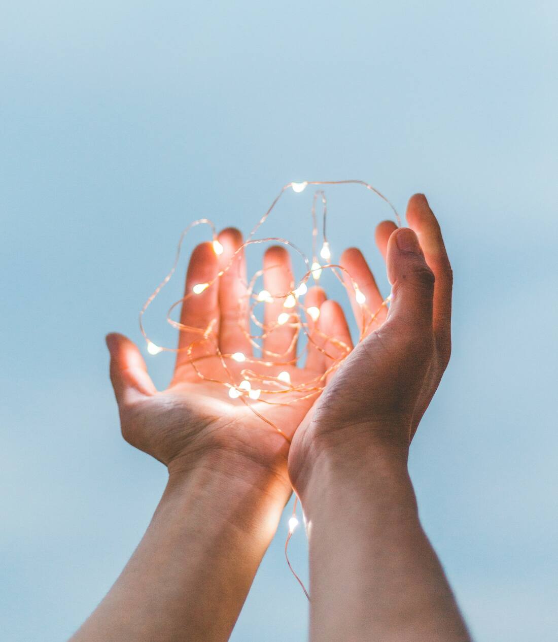 Deux mains ouvertes recueillant une lumière douce et chaleureuse, évocation du magnétisme